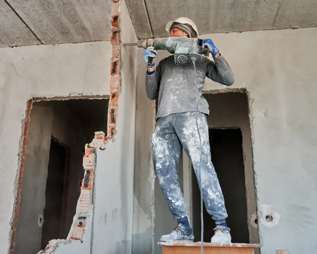 Tradesman removing a damaged interior wall